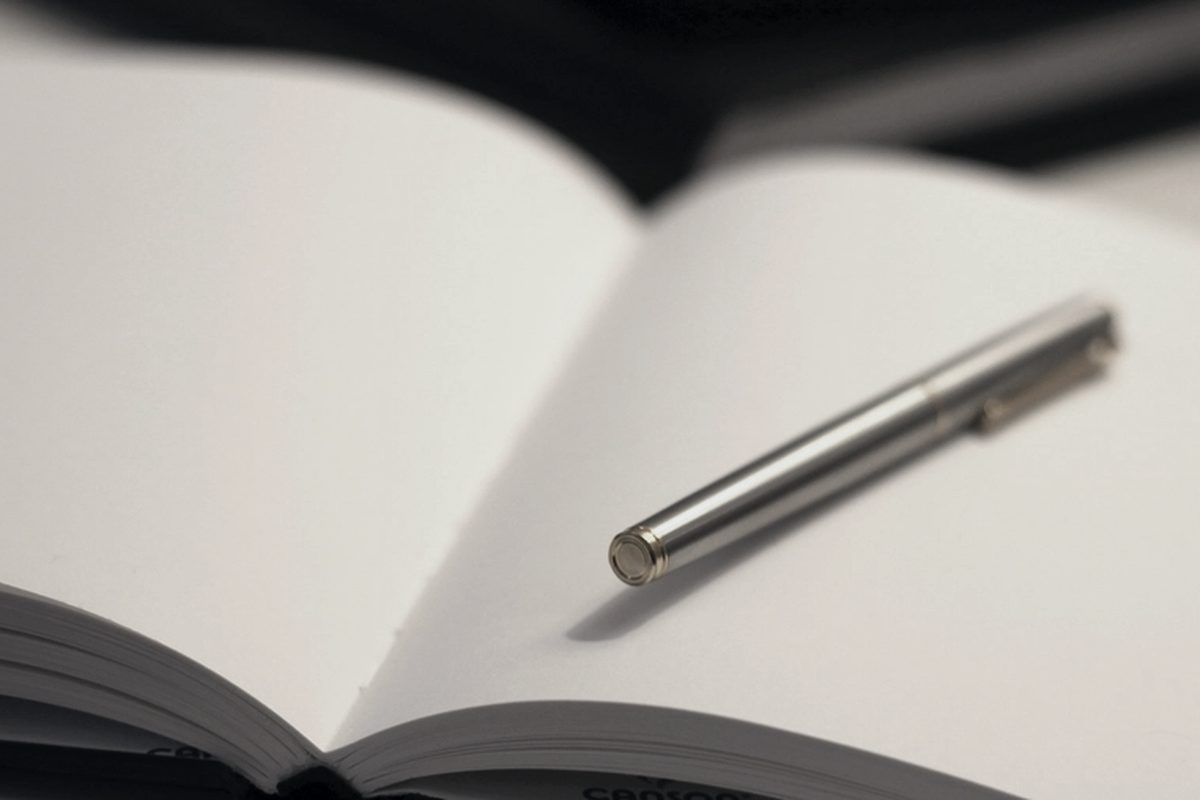 A pen resting on an open bound volume